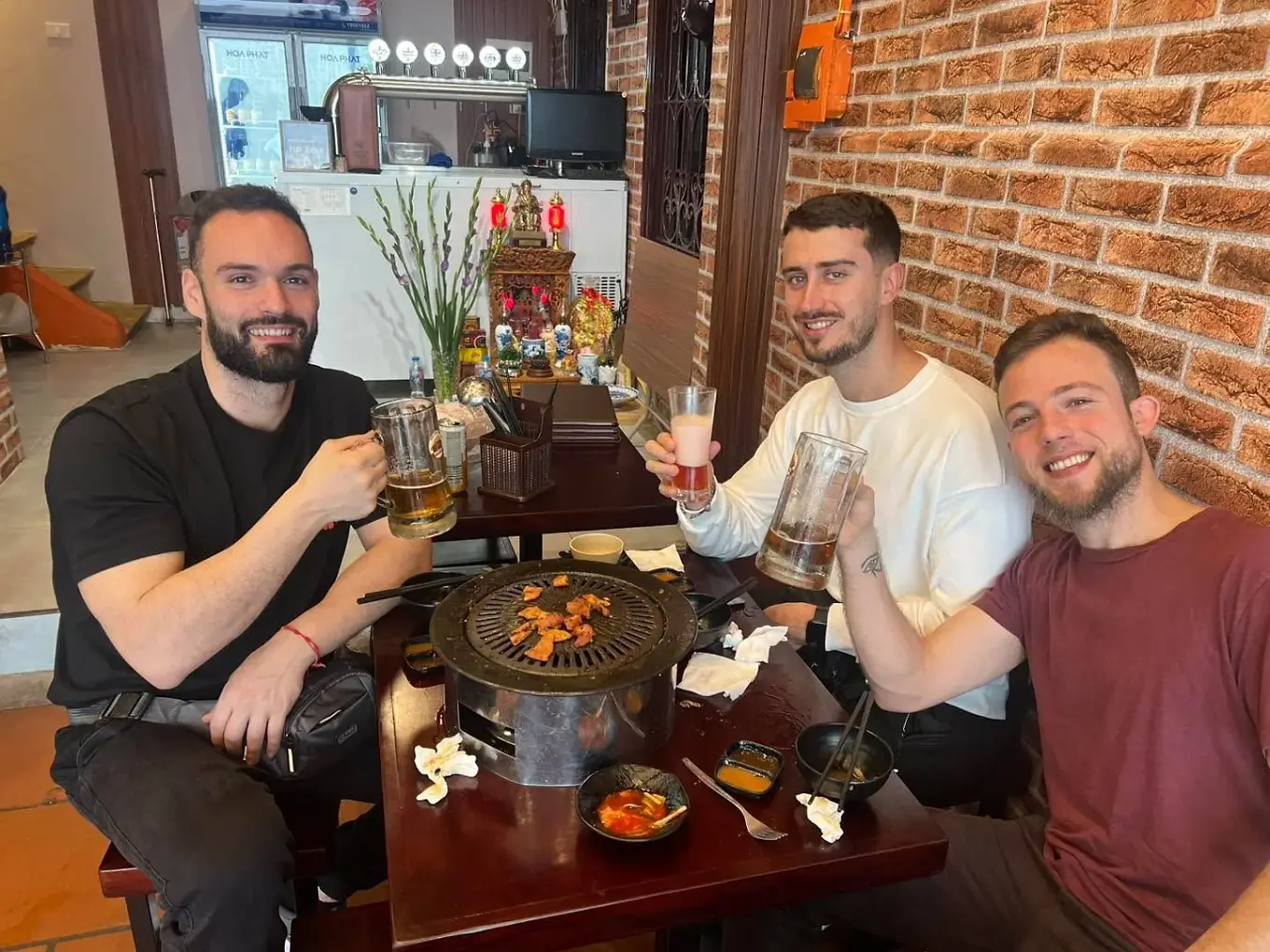Khách nâng ly bia thủ công bên bàn nướng ở Woodfire